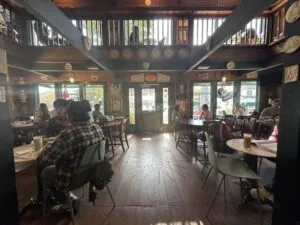 Interior de Agora Houston con decoración ecléctica, luz cálida y clientes disfrutando café artesanal en Montrose.