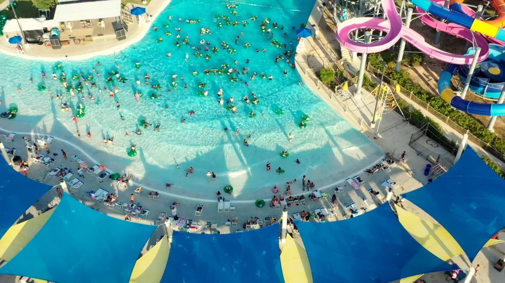 Parques acuáticos Houston con grandes toboganes y piscina de olas llenos de visitantes disfrutando del verano en Texas