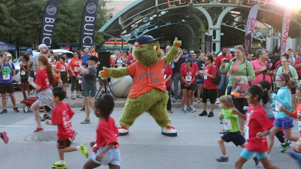 Astros Race to the Pennant con corredores llegando a Daikin Park en evento deportivo con ambiente festivo