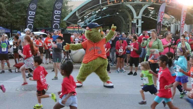 Astros Race to the Pennant con corredores llegando a Daikin Park en evento deportivo con ambiente festivo