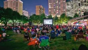familias disfrutando cine al aire libre en parque con pantalla gigante y ambiente nocturno de verano