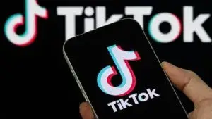 Un adolescente observa videos de TikTok en un teléfono inteligente mientras aparece un mensaje de advertencia sobre retos virales.