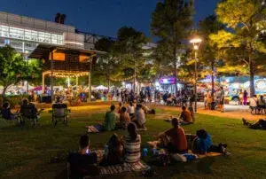 Visitantes recorren un mercado nocturno en Houston con puestos de comida y productos artesanales.