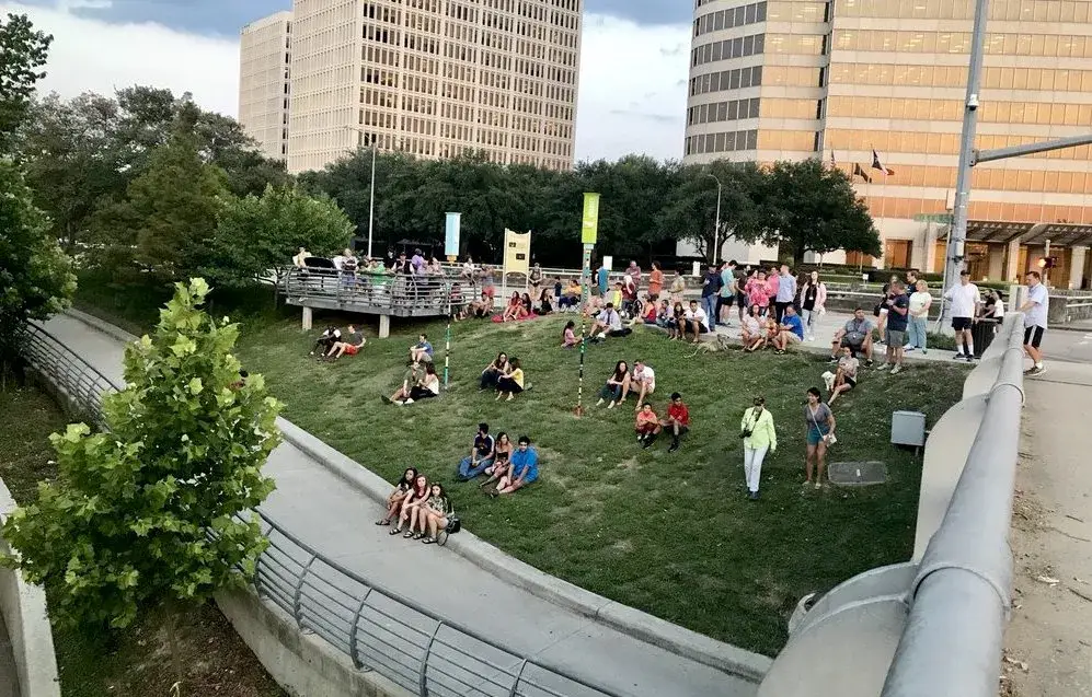 Fotografía real de la colonia de murciélagos volando sobre Buffalo Bayou al atardecer.