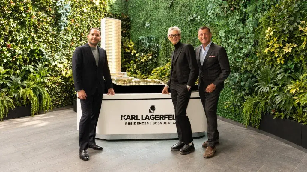 Tres participantes en la presentación de Karl Lagerfeld Residences posan junto a la maqueta del desarrollo inmobiliario en México.