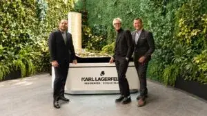 Tres participantes en la presentación de Karl Lagerfeld Residences posan junto a la maqueta del desarrollo inmobiliario en México.