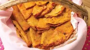 Una canasta tradicional con tacos sudados, tortillas brillantes y salsas mexicanas, en una escena de comida callejera.